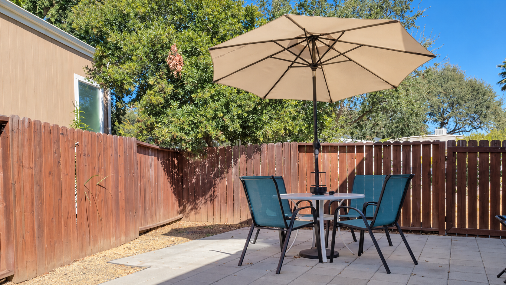 Patio seating beneath an umbrella inside the fenced outdoor space